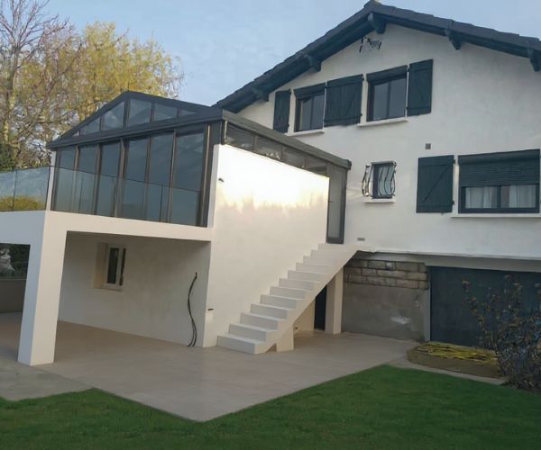 Véranda terminée avec garde-corps vitré et terrasse finie à Villecresnes.